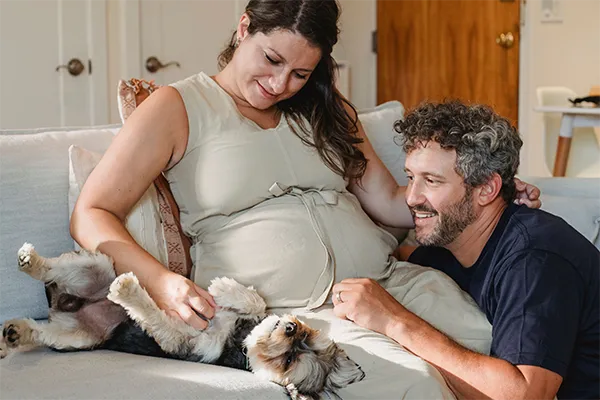 A family portrait. The wife and husband playing with their pet in a sofa